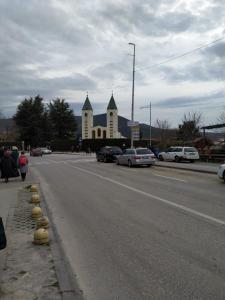 una calle con una iglesia con coches aparcados en la carretera en Apartment GORA, en Međugorje
