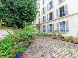 un patio de un edificio con plantas y flores en Au Petit Trianon Bleu, en Versalles