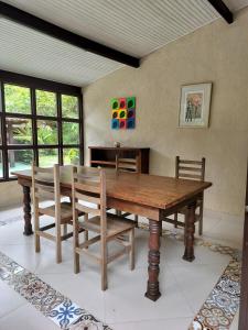 a dining room with a wooden table and chairs at Chalé Pousada da Aldeia in Boicucanga