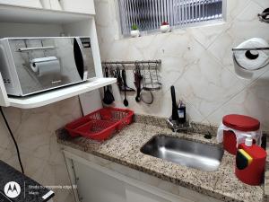 a kitchen counter with a sink and a microwave at Emoções na quadra da praia in Rio de Janeiro