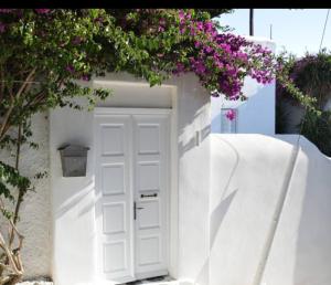 una porta bianca in un muro bianco con fiori viola di Kamara Residence & Suites a Mykonos Città