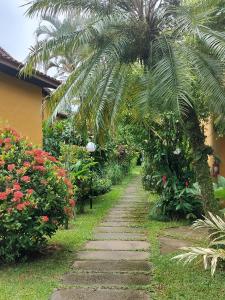 a garden path with a palm tree and flowers at Chalé Pousada da Aldeia in Boicucanga