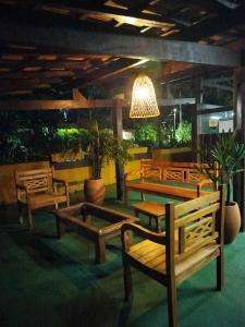 a group of wooden benches in a room with plants at Chalé Pousada da Aldeia in Boicucanga