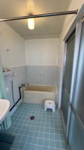 a bathroom with a tub and a toilet in it at Okinawa Naha JinJin -沖縄伝統体験型宿じんじん- in Naha