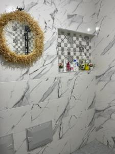 a bathroom with white marble walls and a mirror at شقة تتوفر على جميع شروط الراحة و الامان in Benguerir