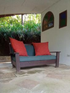 a bench with two red pillows on a patio at Cabina de montaña in San José