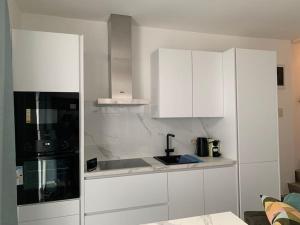 una cocina con armarios blancos y fregadero en Appartement séparé avec parking dans villa, en Vilvoorde