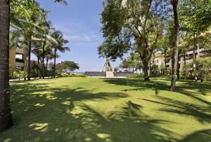 a park with palm trees and a pyramid in the distance at Conrad Bali in Nusa Dua
