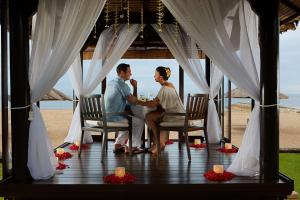 una sposa e uno sposo seduti a un tavolo in un gazebo di Conrad Bali a Nusa Dua