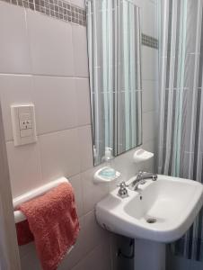 y baño blanco con lavabo y ducha. en Hogareño departamento calle 42 en La Plata
