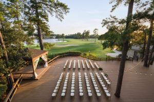 a row of white benches on a deck with a golf course at The Woodlands Resort, Curio Collection by Hilton in The Woodlands