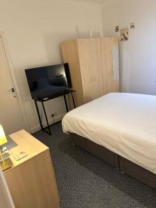 a hotel room with a bed and a flat screen tv at Suite double room in Tottenham. in London