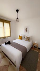 appartement L'OLIVIER في آرل: غرفة نوم بسرير ابيض كبير مع مخدات صفراء