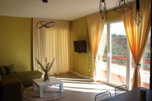 a living room with a couch and a large window at Sunny Home overlooking Tirana in Tirana