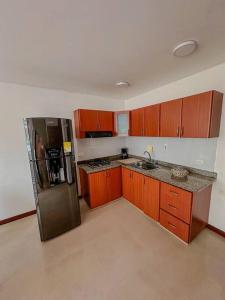 een keuken met houten kasten en een roestvrijstalen koelkast bij Apartamento Duplex en ubicacion privilegiada in Manizales