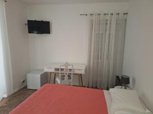 a bedroom with a bed and a desk and a television at Penaferrim Sintra Rooms in Sintra