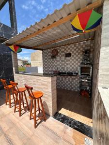 een terras met stoelen en een buitenkeuken met parasol bij Bela Beach in São José da Coroa Grande