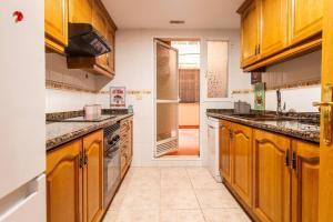een grote keuken met houten kasten en apparaten bij Apartamento familiar centrico in Denia