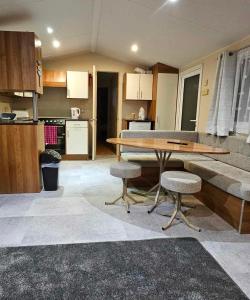 una cucina con tavolo in legno e 2 sgabelli di Sam's Caravan Hire Coastfield Holiday Village Ingoldmells a Ingoldmells