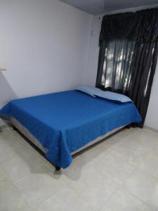 um quarto com uma cama azul e uma janela em Apartamento en el sur de Cali em Cali