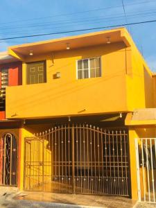 a yellow house with a gate in front of it at CASA ENTERA CERCA DE PRINCIPALES VIAS EN TIJUANA in Tijuana