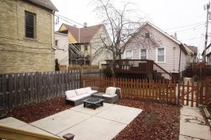 a backyard with a fence and a couch and a table at Renovated Brady St. Classic in Milwaukee