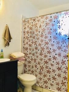 a bathroom with a toilet and a shower curtain with flowers at CASA ENTERA CERCA DE PRINCIPALES VIAS EN TIJUANA in Tijuana