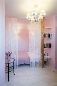 a bedroom with a pink bed and a chandelier at Domek A 145 Miód Malina- Kaszubska Ostoja in Barkocin