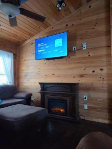 a living room with a fireplace and a flat screen tv at Perfectly Imperfect Cabin in Turtletown