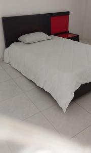 a white bed with a red headboard and white sheets at HOSTAL CARACOLI - HUECO in Valledupar
