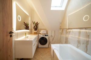 a bathroom with a sink and a tub and a washing machine at Chrobrego Residence in Gniezno
