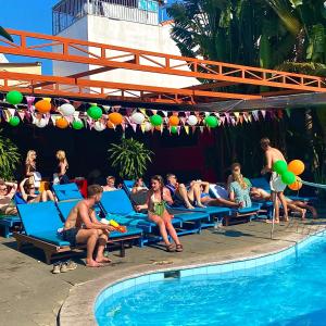a group of people sitting on lounge chairs next to a swimming pool at Bed Station Hostel & Pool Bar Hội An " Former Sunflower" in Hoi An