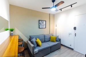 a living room with a blue couch and yellow pillows at Apto 1 quarto, Centro, Cambuí, Guanabara, 1 vaga garagem, prox. a mercado, academia, hospital in Campinas