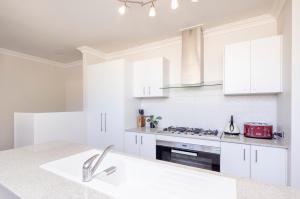 a kitchen with white cabinets and a stove top oven at Urban Retreat Townhouse near CBD in Perth