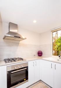 a white kitchen with a stove and a window at Urban Retreat Townhouse near CBD in Perth