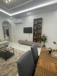 a living room with a couch and a table and a tv at شقق فندقيه فاخره بتصمم عصري ودخول ذاتي in Jeddah