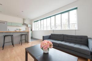 een woonkamer met een bank en een tafel bij Modern Luxury Apartment by Bow Road Station in Londen