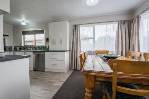 eine Küche und ein Esszimmer mit einem Holztisch in der Unterkunft Beez Kneez in Rotorua