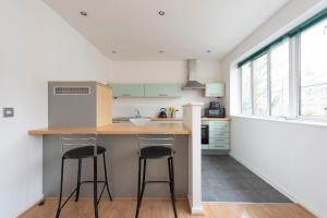 a kitchen with two bar stools and a counter top at Modern Luxury Apartment by Bow Road Station in London