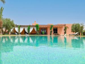 une grande piscine d'eau en face d'un bâtiment dans l'établissement Villa Soraya/Noor Hotel & Spa, à Marrakech