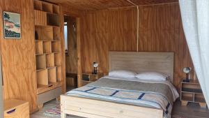 sypialnia z łóżkiem i drewnianymi ścianami w obiekcie Surf and Stay Chile w mieście Navidad