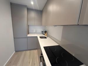 a kitchen with white cabinets and a black stove top oven at 1BR Luxury Flat at Train station - Long stays welcome - just ask in Milton Keynes