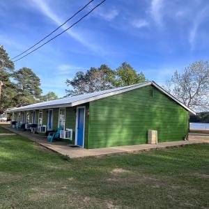 a green building with chairs in front of it at Alpine Lakeview Motel Room WiFi,Sandy beach Boat Ramp,Pier,Marina,Bath House with Laundromat in Hemphill