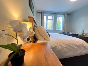 Un dormitorio con una cama y una mesa con una flor en 1BR Flat MK Centre - Free Parking - Private Garden - Long stays welcome - just ask en Milton Keynes