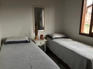 Duas camas individuais num quarto com um espelho. em Sobrado,Armação -Sul da Ilha-Floripa em Florianópolis
