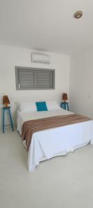 a white bedroom with a large bed with two stools at Pontal Praia Suítes in Fortim