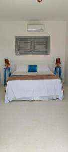 a bedroom with a white bed with two tables at Pontal Praia Suítes in Fortim