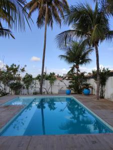 a swimming pool with palm trees in the background at Pontal Praia Suítes in Fortim