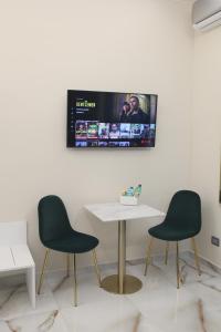 a table with two chairs and a tv on a wall at Napoli Central Suites in Naples