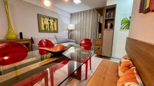 sala de estar con mesa de cristal y sillas rojas en Edf Duetto 2 QTS c/ar, en Maceió